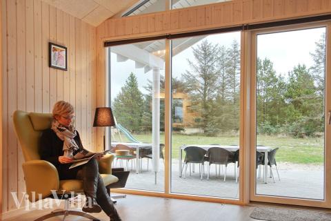 Das Wohnzimmer mit Sicht in den Garten ist mit bequemen Möbeln, Kaminofen und Flachbild-TV geschmackvoll eingerichtet