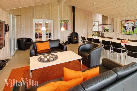 Stuen, som har udsigt til haven, er smagfuldt indrettet med komfortable møbler, brændeovn og et stort fladskærms-tv