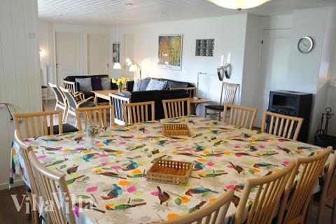 Der Aufenthaltsraum ist der natürliche Sammelpunkt des Hauses, mit Kochbereich, Speiseplätzen, Kaminofen und einer Sofagruppe mit Flachbild-TV