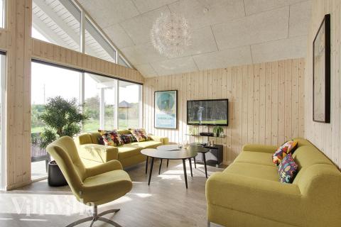 Das Wohnzimmer mit Sicht in den Garten ist mit bequemen Möbeln, Kaminofen und Flachbild-TV geschmackvoll eingerichtet